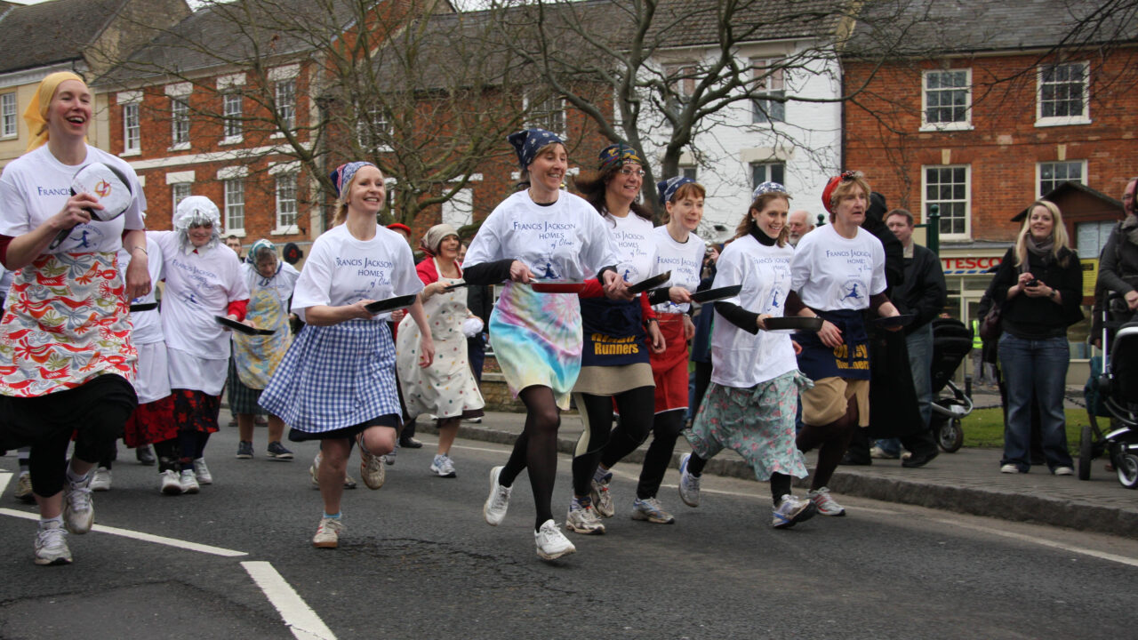 Pancake Racing Flipping and Sprinting in Aprons on Shrove Tuesday in Buckinghamshire, England