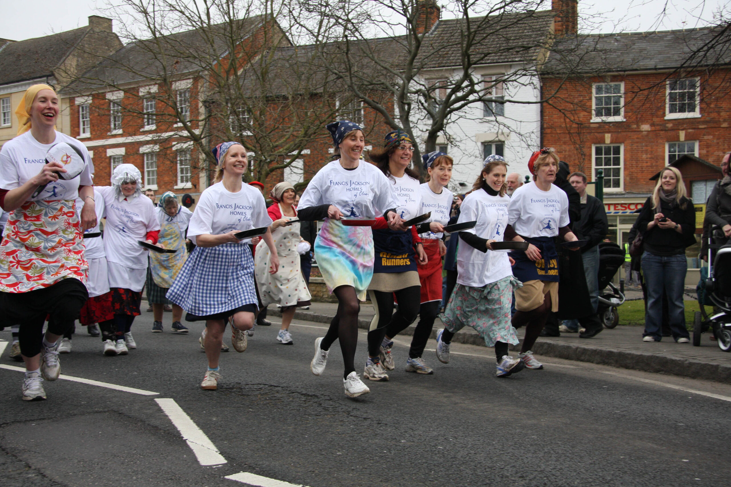 Pancake Racing. Flipping and Sprinting in Aprons on Shrove Tuesday in Buckinghamshire, England